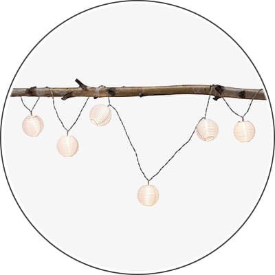 Fünf runde Laternen hängen an einem Ast und leuchten warmweiß.