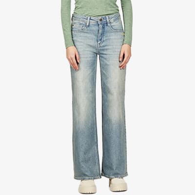 Person trägt eine hellblaue, weite Jeans und ein langärmeliges grünes Oberteil.