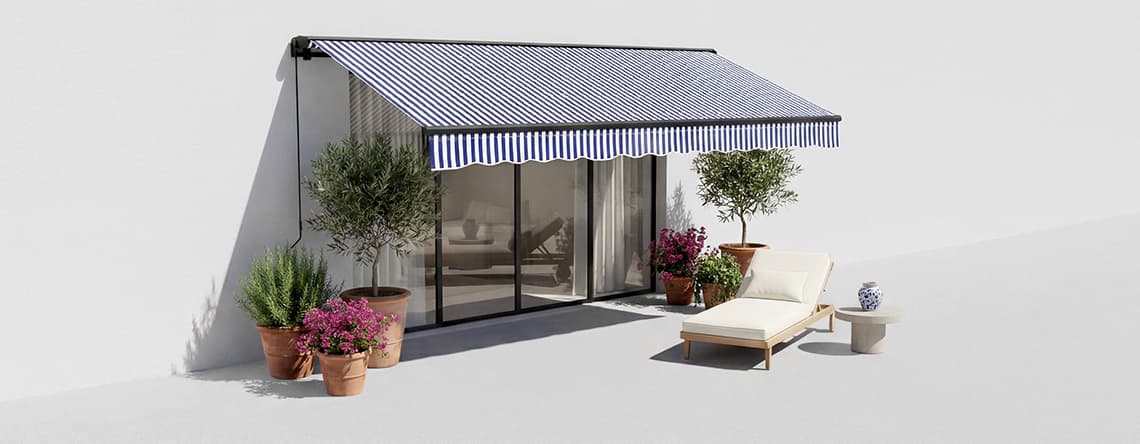 Markise mit blau-weißen Streifen über Terrasse mit Pflanzen und Liegestuhl vor einer Glasschiebetür