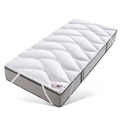 Weiße Matratzenauflage mit gestepptem Muster auf grauer Matratze.