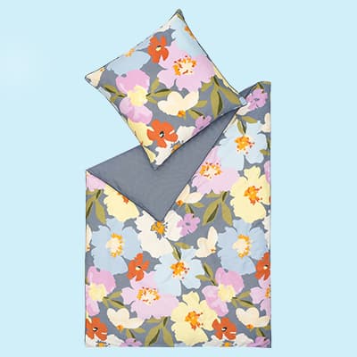 Bettwäsche-Set mit bunten Blumen auf grauem Hintergrund, ein Kissen und eine Decke.