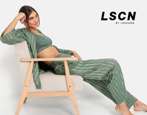 LSCN by Lascana – Frau in grüner Unterwäsche und passendem Morgenmantel lehnt sich entspannt in einem Stuhl zurück