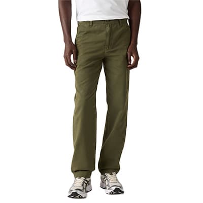 Mann steht frontal in olivgrüner Hose und weißen Turnschuhen, T-Shirt teilweise sichtbar