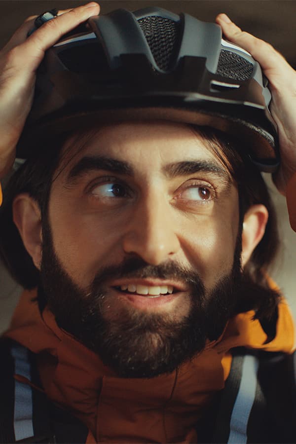 Person setzt sich einen Fahrradhelm auf und trägt eine Outdoorjacke