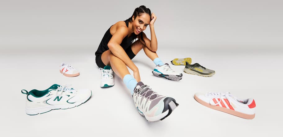 Person in Sportkleidung sitzt umgeben von verschiedenen Sneakers, ein Schuh groß im Vordergrund