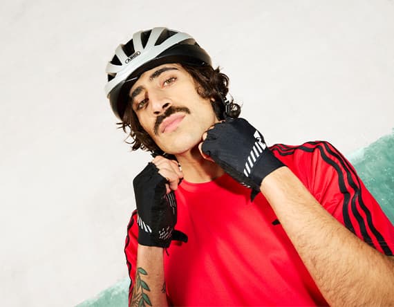 Person im roten Sportshirt mit Helm und Fahrradhandschuhen hebt beide Fäuste vor die Brust