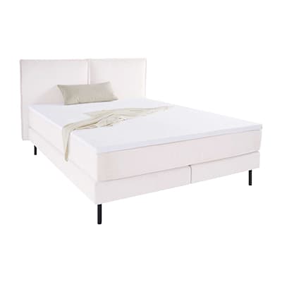 LeGer Helles Boxspringbett mit hohem Kopfteil, weißer Decke und grauem Kissen auf schlanken schwarzen Füßen