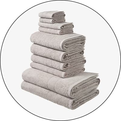 Gestapeltes Set aus großen und kleinen hellen Handtüchern in mehreren Reihen vor weißem Hintergrund