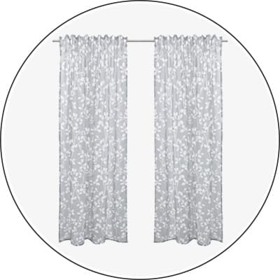 Zwei lange Vorhänge mit hellem Blumenmuster hängen dicht gerafft an einer Gardinenstange