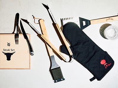 Steak Set mit Grillbesteck, Grillbürste und schwarzer Tasche auf hellem Untergrund