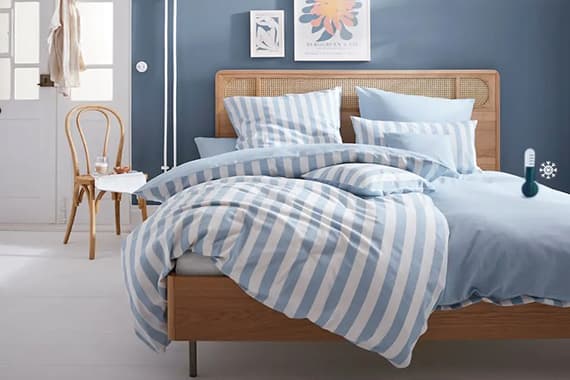 Doppelbett mit blau gestreifter Bettwäsche in modernem Schlafzimmer mit Holzstuhl und Wandbild