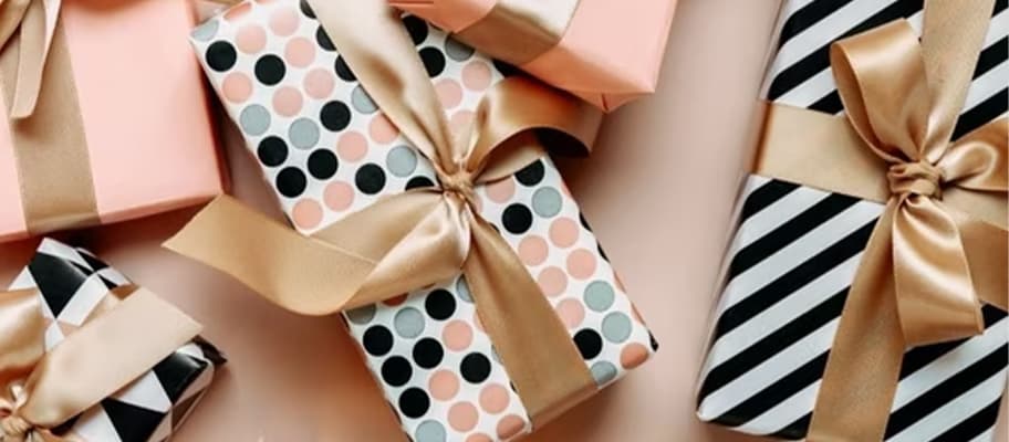 Mehrere bunt gemusterte Geschenke mit Schleifen liegen dicht nebeneinander auf hellem Untergrund