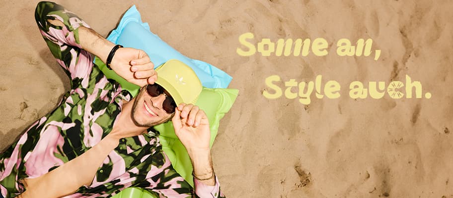 Sonne an, Style auch. Mann mit Cap und Sonnenbrille liegt entspannt auf buntem Luftkissen im Sand