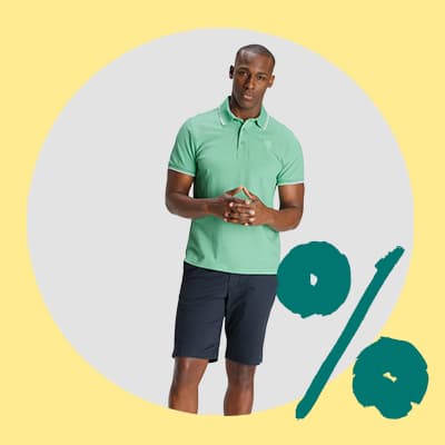 Mann in grünem Poloshirt und dunkler Shorts steht vor hellem Hintergrund mit großem Prozentzeichen daneben