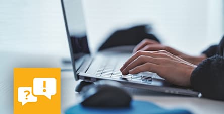 Person tippt auf Laptop-Tastatur, daneben Computermaus, links gelbes Symbol mit Sprechblasen und Ausrufezeichen