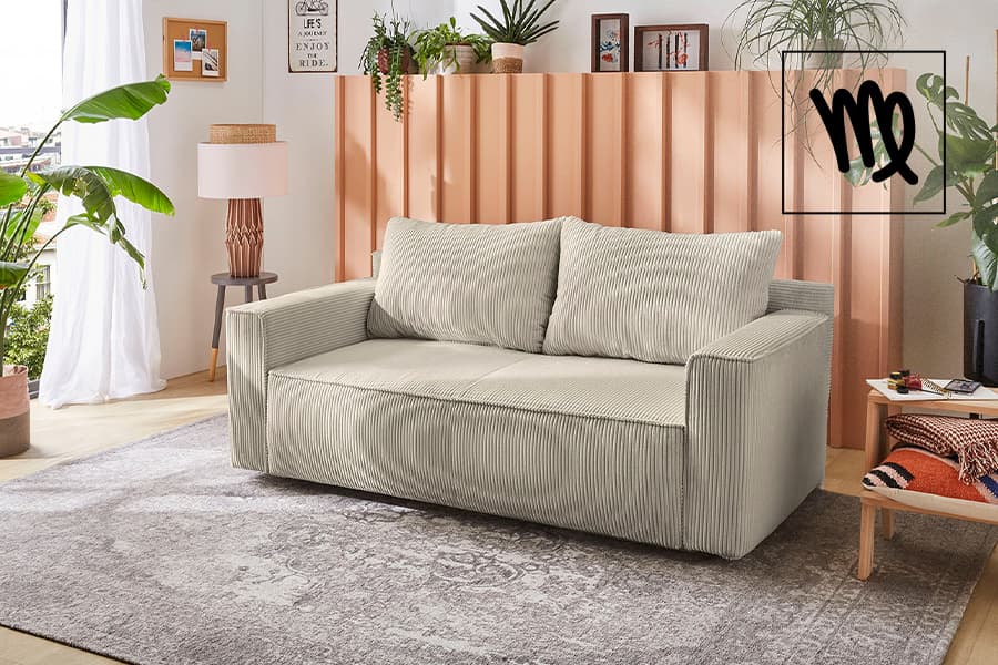 Zweisitzer-Sofa mit breiten Kissen in hellen Streifen, davor Teppich, umgeben von Pflanzen und Wohnaccessoires