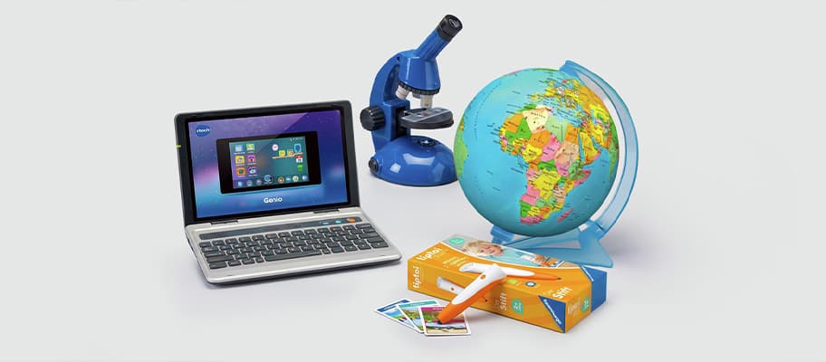Lernset mit Kinderlaptop, blauem Mikroskop, bunter Weltkugel und Hörstift mit Karten auf hellem Hintergrund