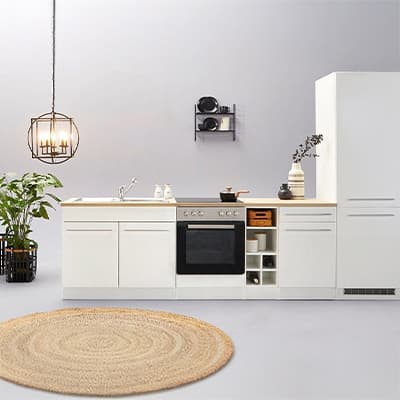 Moderne weiße Küche mit Herd, Spüle, Hängelampe, grünem Pflanzen und rundem Teppich auf grauem Boden