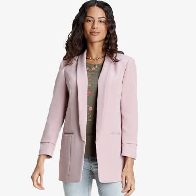 Frau trägt rosa Blazer über grünem Shirt mit Blumenmuster und hellblauen Jeans