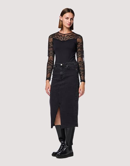 Frau mit langen, dunklen Haaren trägt langärmliges Kleid mit schwarzem und weißem Blumenmuster