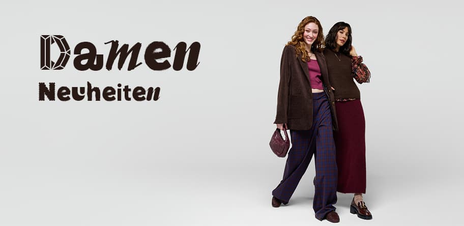 Damen Neuheiten – Zwei Frauen in herbstlicher Kleidung posieren zusammen, eine trägt karierte Hose, die andere einen langen Rock.