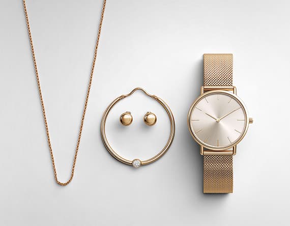 Goldene Halskette, runde Ohrringe, Armreif mit Stein und Uhr mit goldfarbenem Armband auf weißem Hintergrund