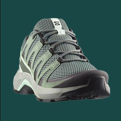 Grauer Sportschuh mit grünen Akzenten und schwarzer Sohle, Ansicht von vorne, auf dunkelgrünem Hintergrund