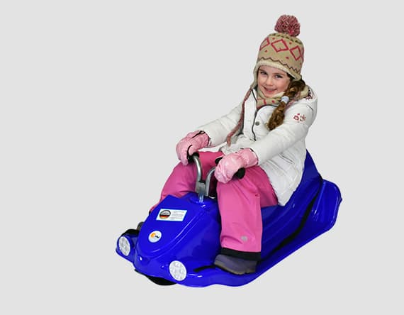 Kind in Winterkleidung fährt auf einem blauen Schlitten.