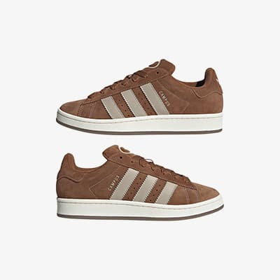 Zwei braune Sneakers mit weißen Streifen und weißer Sohle, seitlich gezeigt.