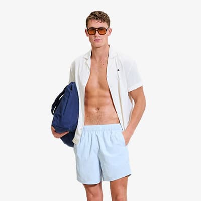 Mann mit offener Hemdbluse und hellen Shorts trägt eine große dunkelblaue Tasche über der Schulter